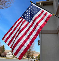 American flag waving on a flagpole against a clear blue sky.