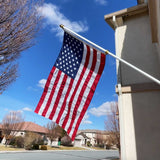 American flag waving in front of a house with a clear blue sky.